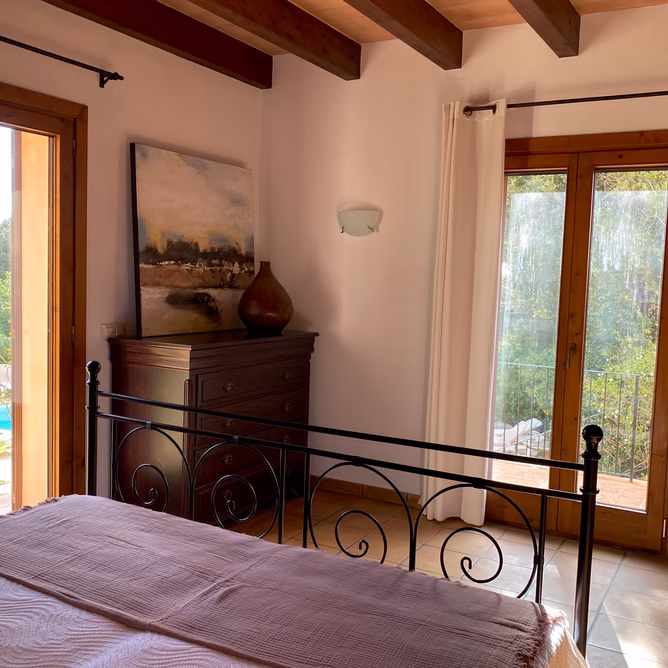 Schlafzimmer mit schmiede­eisernem Bett und Gartenblick