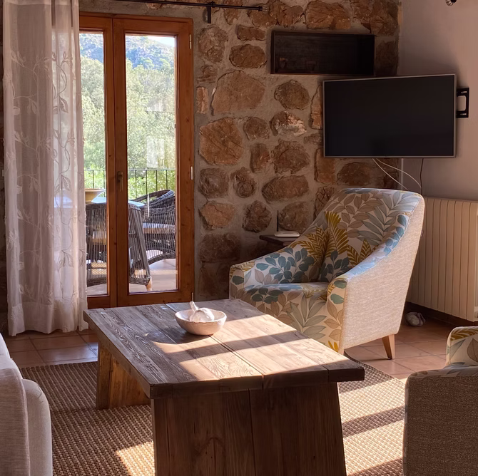 Wohnzimmer mit Naturstein­wand und Smart-TV