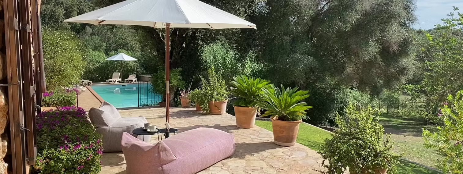 Pool­terrasse mit Sonnenschirm und Loungemöbeln
